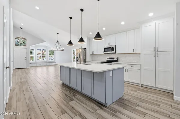 a kitchen with kitchen island granite countertop wooden floors white cabinets and stainless steel appliances