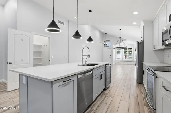 a kitchen with stainless steel appliances a sink a stove a refrigerator and island with wooden floor