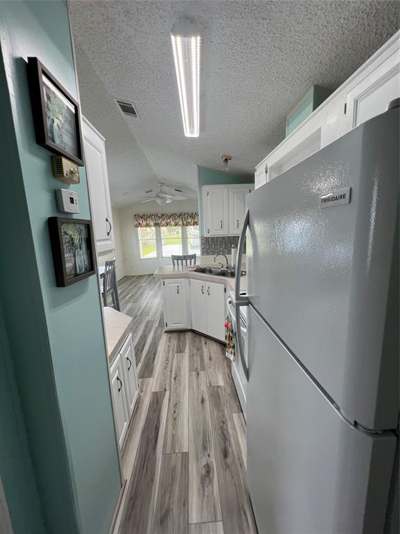 13891 Southeast 126th Boulevard, Unit 121 Okeechobee, FL 34974 - Photo 5 of 45 a kitchen with granite countertop a refrigerator a sink a stove and wooden floor