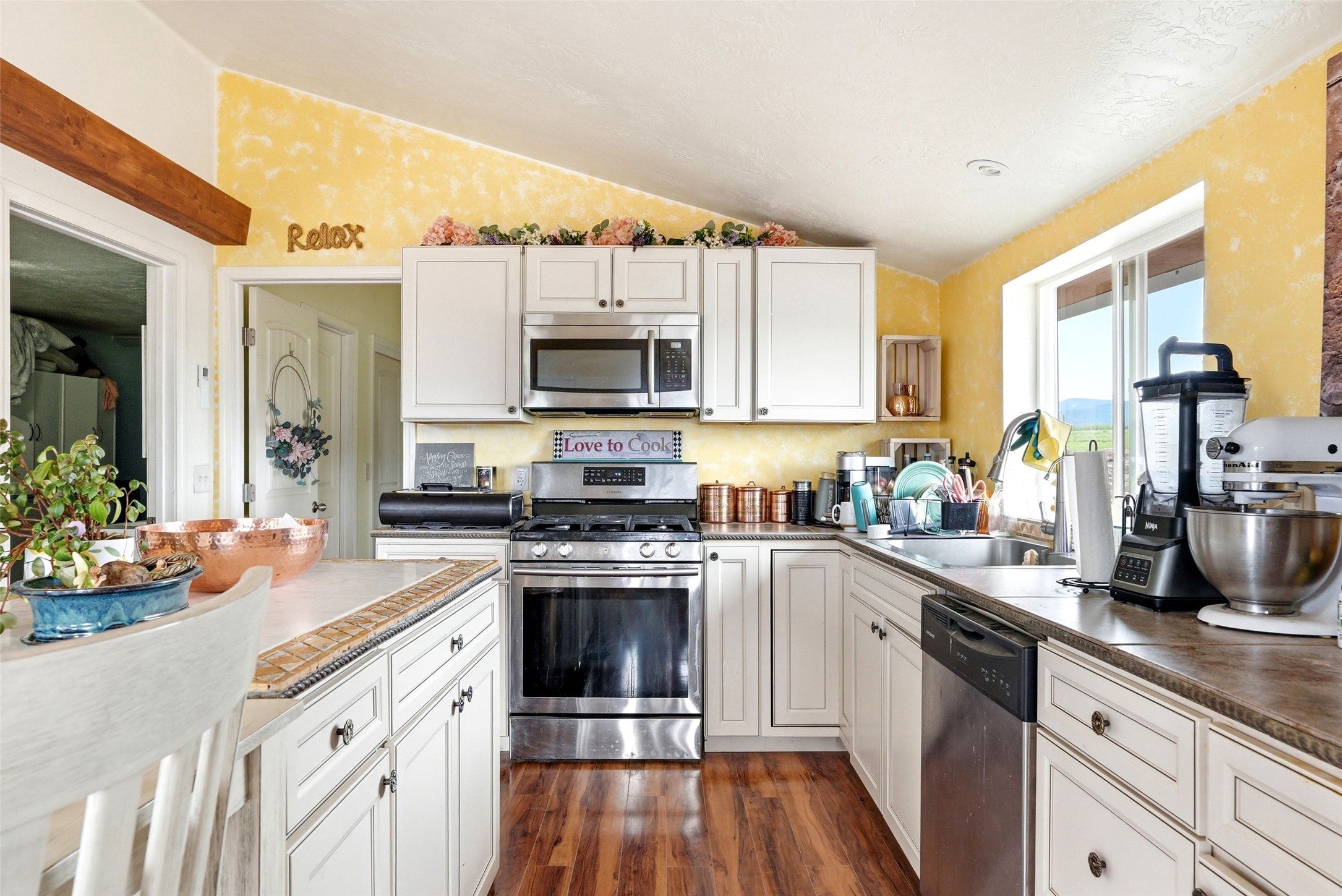 679 Hidden Valley Road North Florence, MT 59833 - Photo 64 of 85 Kitchen featuring wood-finish flooring, white cabinetry, stainless steel appliances, and a window above the sink