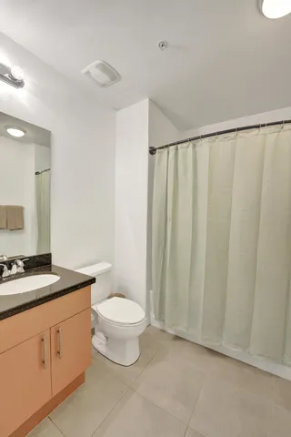 a spacious bathroom with a granite countertop sink a toilet and a mirror