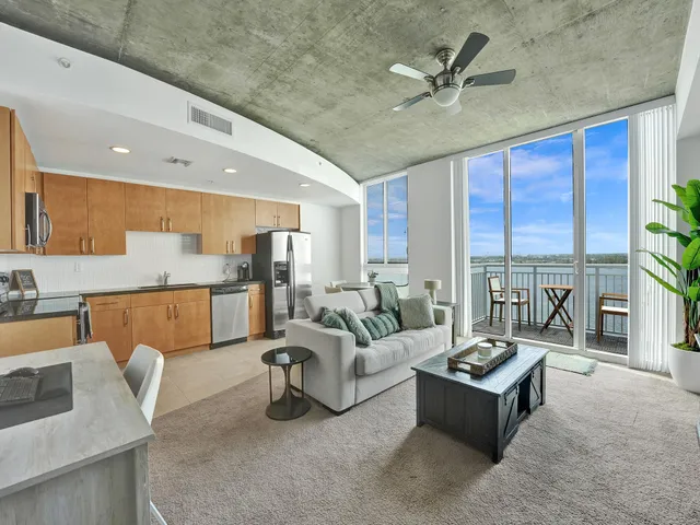 a living room with furniture ceiling fan and a large window
