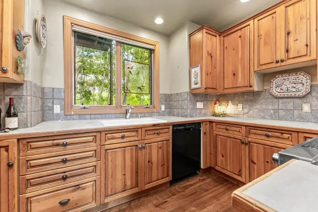a kitchen with stainless steel appliances granite countertop a sink and cabinets with wooden floor