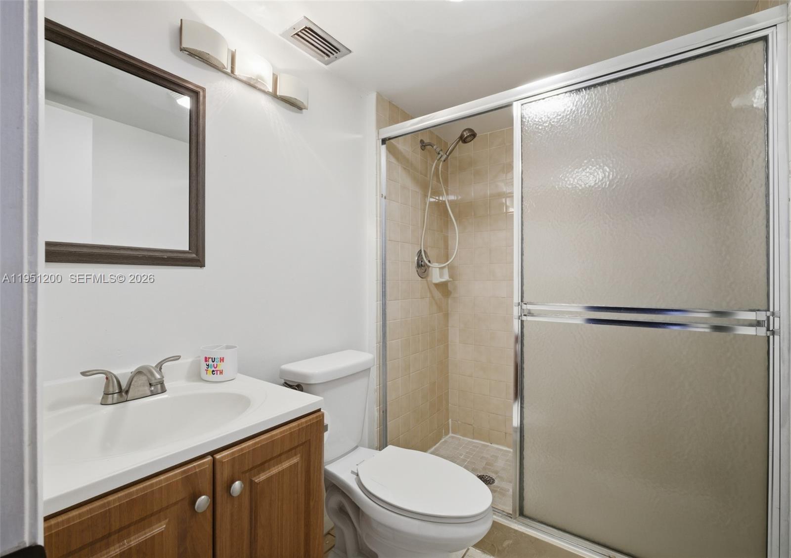 23024 Oxford Place, Unit C Boca Raton, FL 33433 - Photo 13 of 22 a bathroom with a sink a mirror a toilet and shower