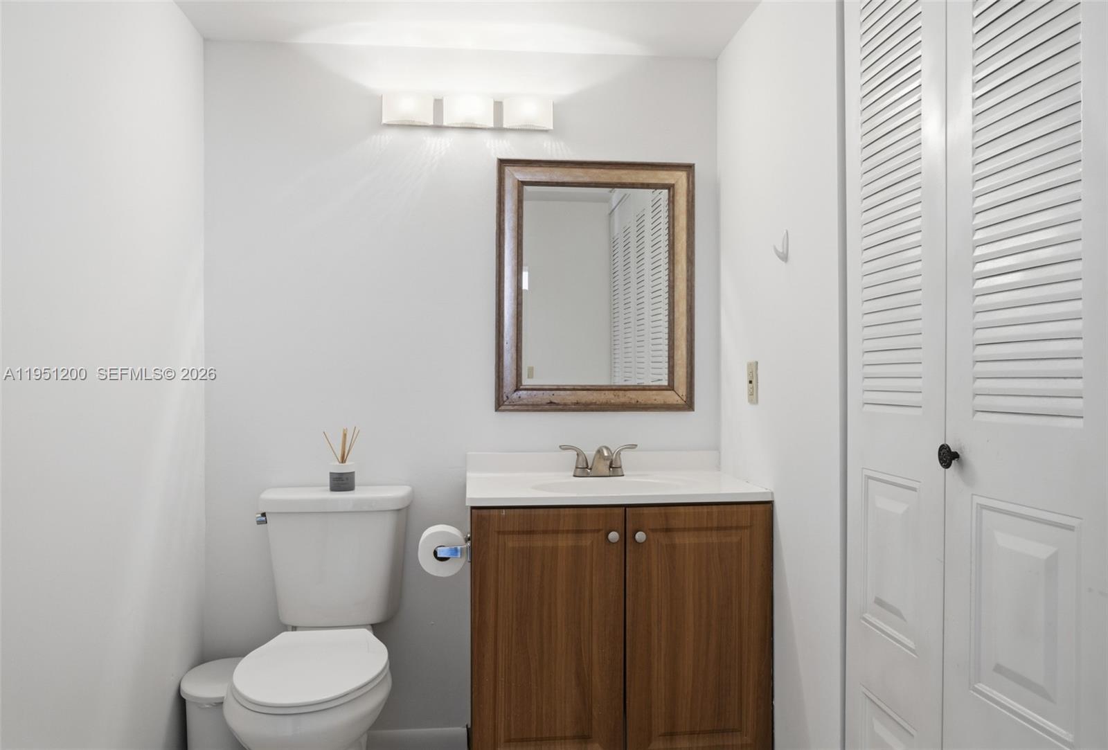 23024 Oxford Place, Unit C Boca Raton, FL 33433 - Photo 14 of 22 a bathroom with a toilet a sink and mirror