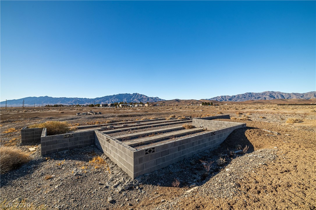4051 Forest Road Pahrump, NV 89048 - Photo 5 of 15 A desert landscape unfolds with distant mountains under a cloudless sky, featuring concrete block foundations.