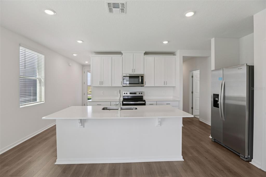 643 Pennywort Street Lake Alfred, FL 33850 - Photo 17 of 47 a large kitchen with stainless steel appliances granite countertop a stove a sink a refrigerator and white cabinets with wooden floor