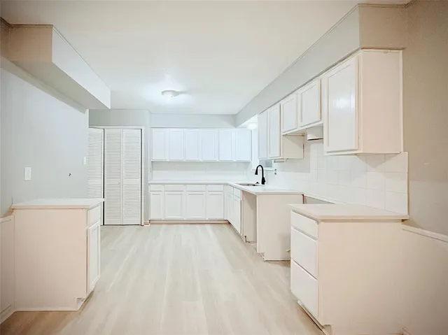 a kitchen with a sink a stove cabinets and wooden floor