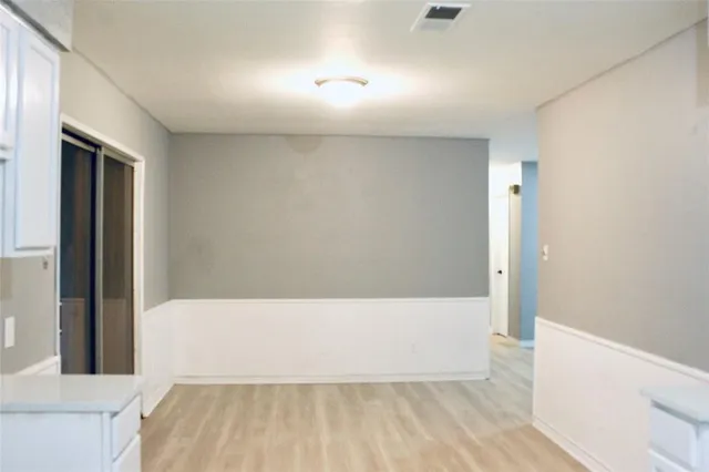 a view of an empty room with wooden floor and a ceiling fan