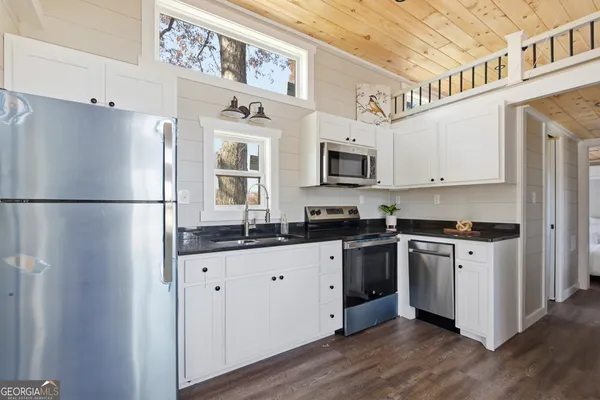 a kitchen with granite countertop a refrigerator stove top oven and sink
