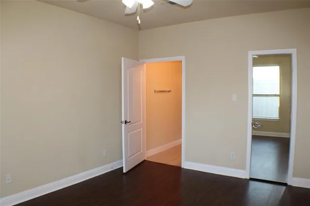an empty room with wooden floor cabinet and windows