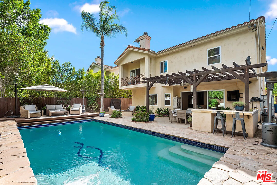 a view of a house with backyard sitting area and swimming pool