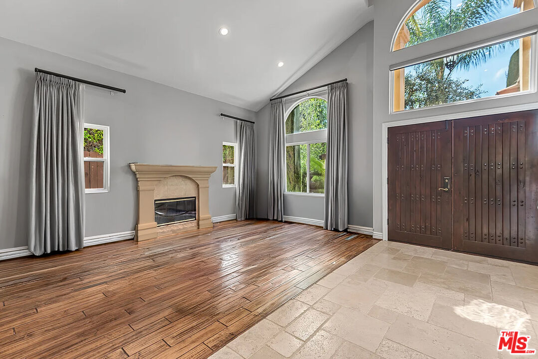 4724 Noble Avenue Sherman Oaks, CA 91403 - Photo 6 of 35 an empty room with windows a fireplace and a wooden floor