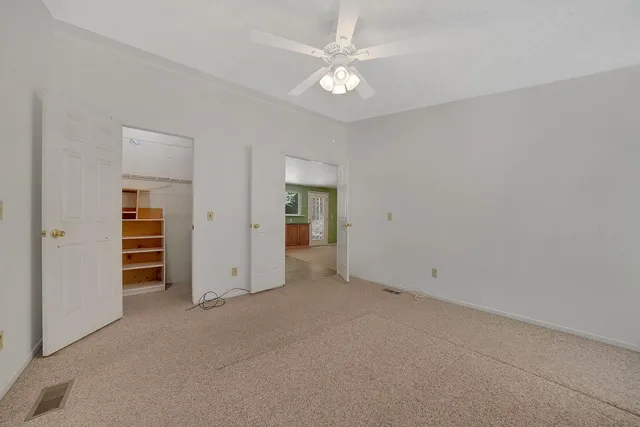 an empty room with closet and a ceiling fan