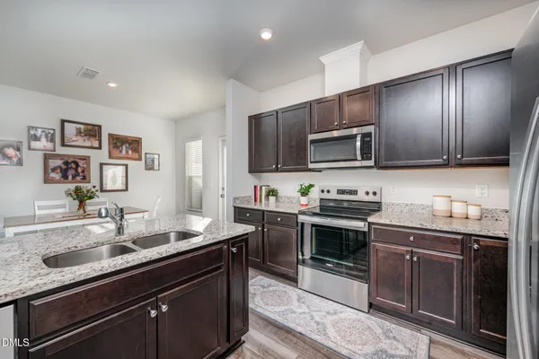 a kitchen with stainless steel appliances granite countertop a sink a stove and a wooden floors