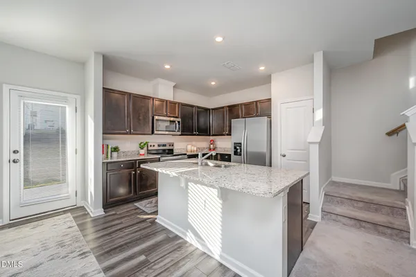 a kitchen with kitchen island granite countertop a sink stove and refrigerator