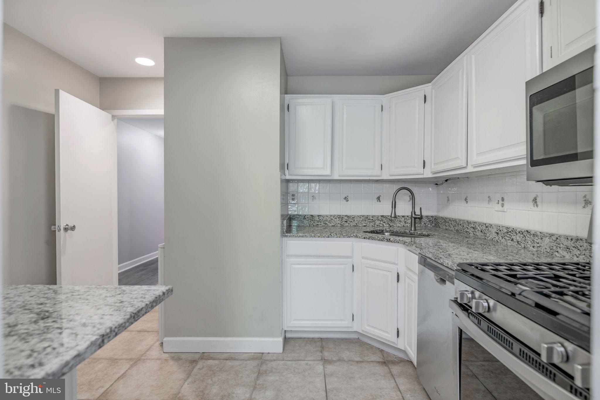 1443 Northgate Square, Unit 22B Reston, VA 20190 - Photo 9 of 42 a kitchen with granite countertop a sink stove and cabinets