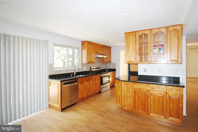 a kitchen with stainless steel appliances granite countertop a stove a sink and a microwave