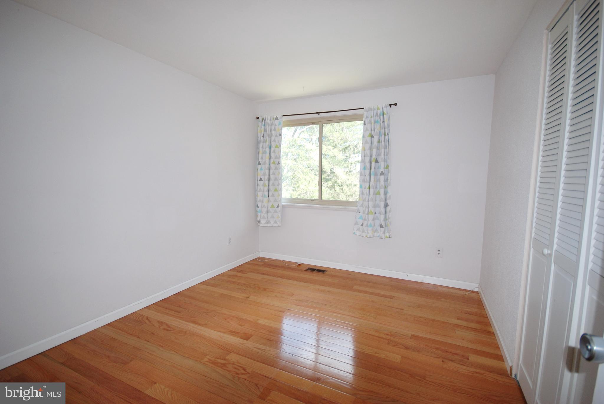 11609 Piney Lodge Road North Potomac, MD 20878 - Photo 17 of 25 a view of an empty room with wooden floor and a window