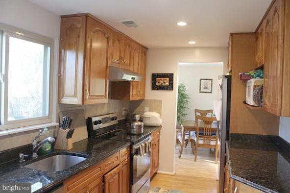 11609 Piney Lodge Road North Potomac, MD 20878 - Photo 5 of 25 a kitchen with granite countertop a sink stove and cabinets
