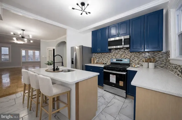 a kitchen with stainless steel appliances wooden cabinets a stove a sink a dining table and chairs