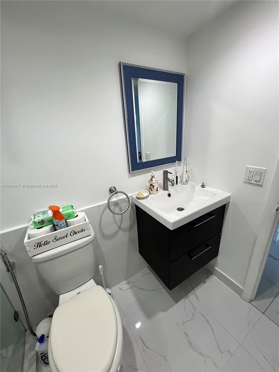 680 Northeast 64th Street, Unit A501 Miami, FL 33138 - Photo 18 of 30 a bathroom with a sink mirror and toilet