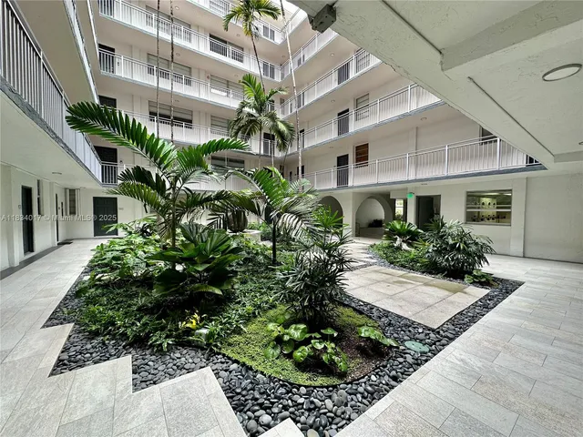 a front view of a multi story residential apartment building with yard and bench