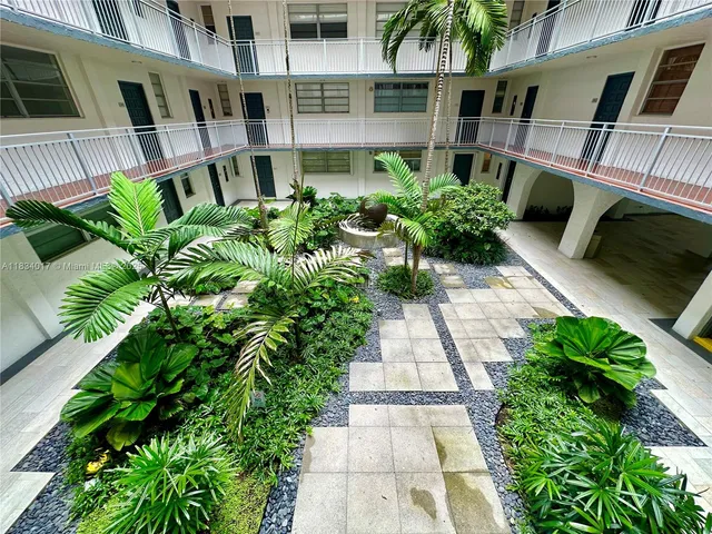 a view of a multi story residential apartment building with a yard