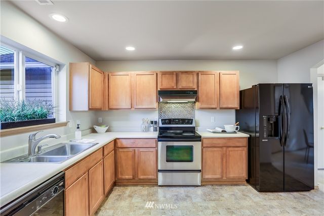 a kitchen with stainless steel appliances granite countertop a sink stove refrigerator and cabinets