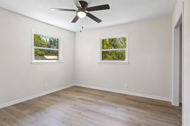 a view of an empty room with wooden floor and window