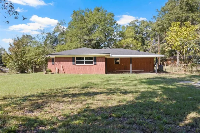 a front view of house with yard and trees in the background