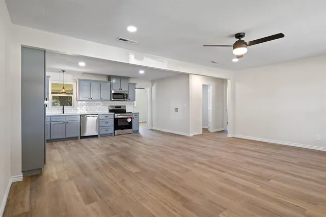 a view of a kitchen with a sink and dishwasher a oven with wooden floor
