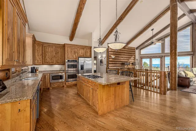 a kitchen with stainless steel appliances kitchen island granite countertop a table chairs and a wooden floors