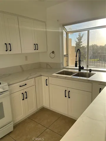 a kitchen with white cabinets and a window