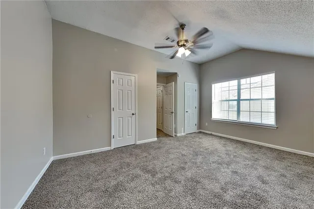 an empty room with windows and fan
