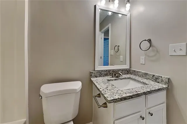 a bathroom with a granite countertop sink and a toilet