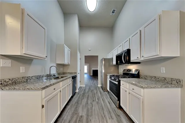 a kitchen with stainless steel appliances granite countertop a stove top oven a sink a microwave and cabinets