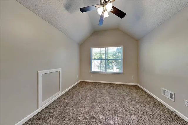 an empty room with a chandelier fan and windows