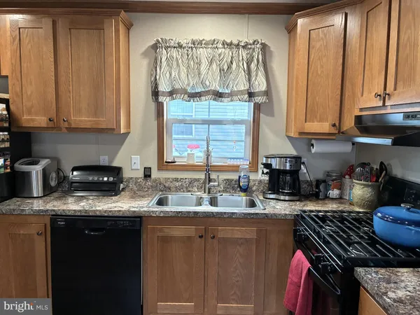 a kitchen with granite countertop a stove a sink dishwasher and cabinets with wooden floor