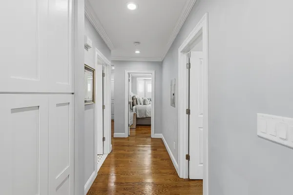 a view of a hallway with wooden floor and a bathroom