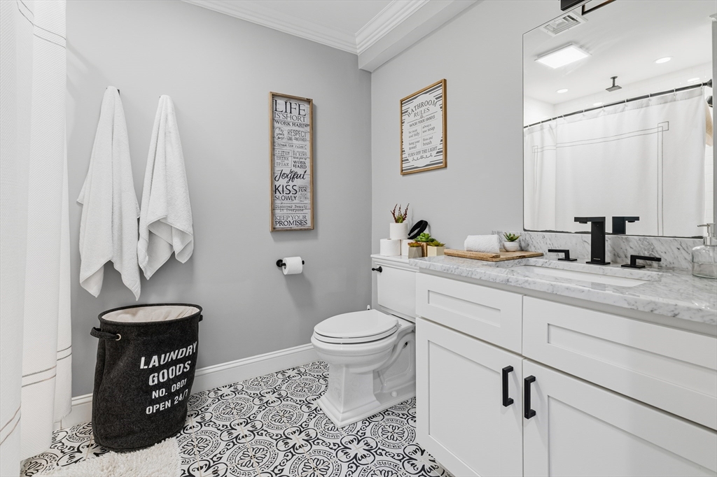 491 Washington Street, Unit 1 Braintree, MA 02184 - Photo 36 of 42 a bathroom with a granite countertop toilet sink and a mirror