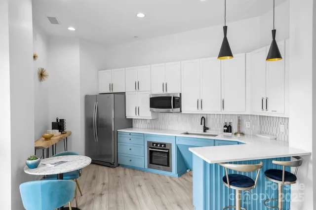 a kitchen with stainless steel appliances granite countertop a sink a stove a refrigerator and island with wooden floor