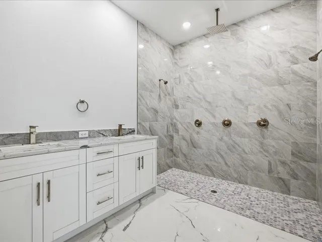 a bathroom with a granite countertop sink a mirror and a shower