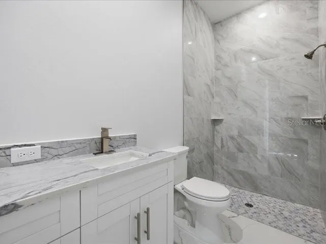 a bathroom with a granite countertop toilet a sink and a shower