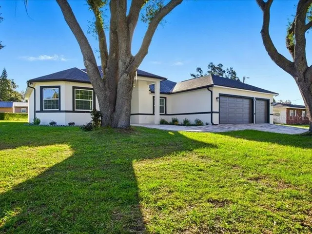 a view of a house with a big yard potted plants and large tree