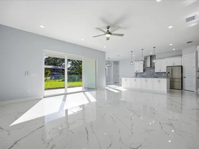 a view of an empty room with kitchen appliances and a ceiling fan