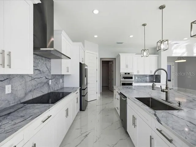 a large kitchen with granite countertop a sink and a refrigerator
