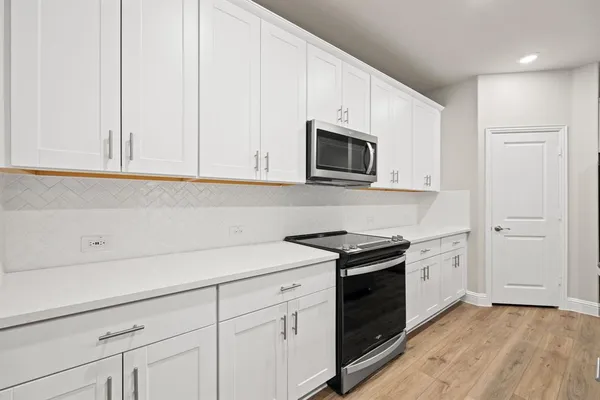 a kitchen with granite countertop white cabinets and stainless steel appliances