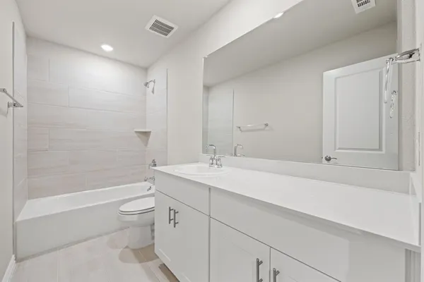 a bathroom with a bathtub shower sink vanity and toilet