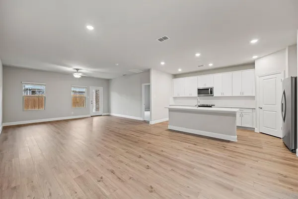 a large white kitchen with kitchen island a sink dishwasher a stove and a refrigerator with wooden floor